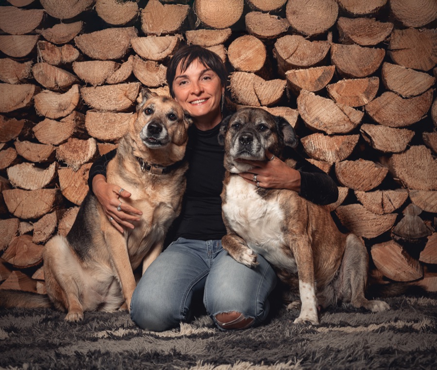 Rita Romayev kneeling between two senior dogs